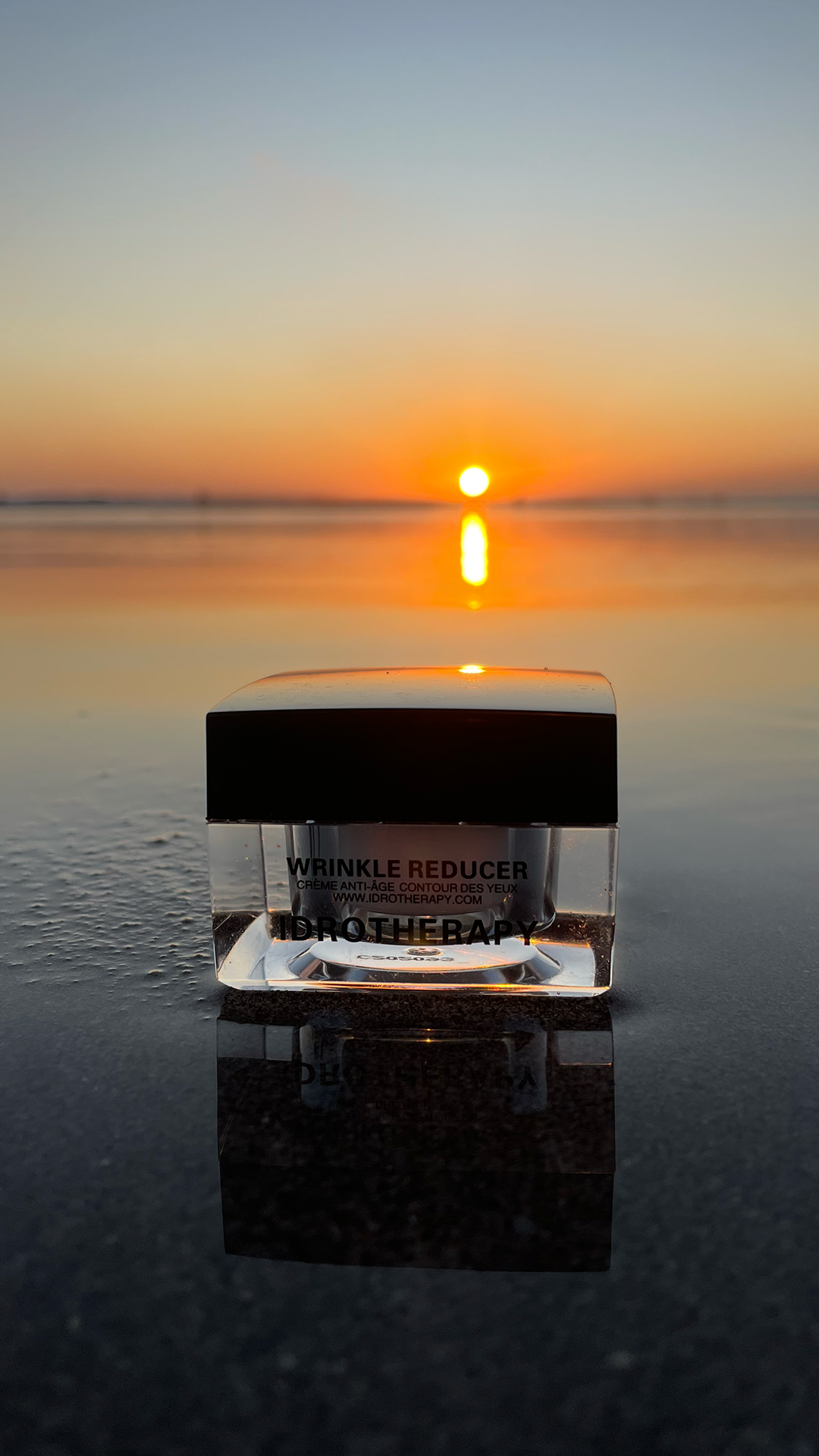 Jar of Idrotherapy Wrinkle Reducer on the sand at sunset